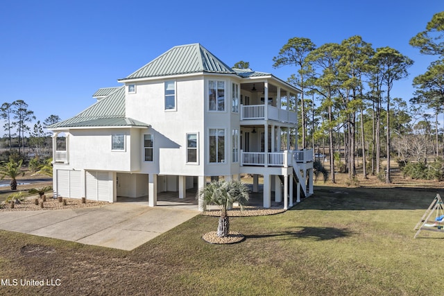 back of property with concrete driveway, a balcony, a lawn, a carport, and metal roof