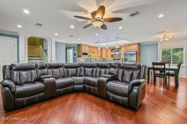 home theater room featuring dark wood-type flooring, crown molding, and ceiling fan