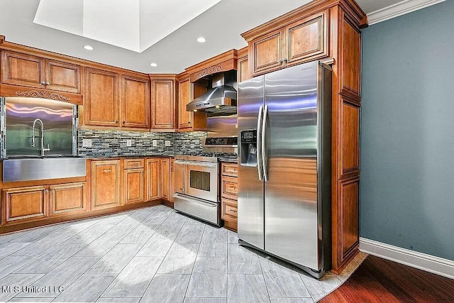 kitchen featuring sink, backsplash, light hardwood / wood-style floors, stainless steel appliances, and wall chimney exhaust hood