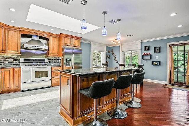 kitchen with a kitchen island, range, light hardwood / wood-style floors, wall chimney exhaust hood, and stainless steel refrigerator with ice dispenser