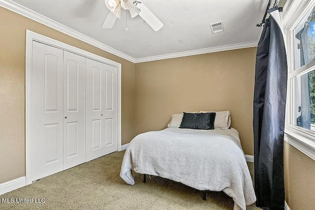 bedroom featuring a closet, ornamental molding, carpet, and ceiling fan