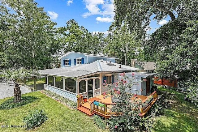 back of house featuring a wooden deck, a yard, and a sunroom