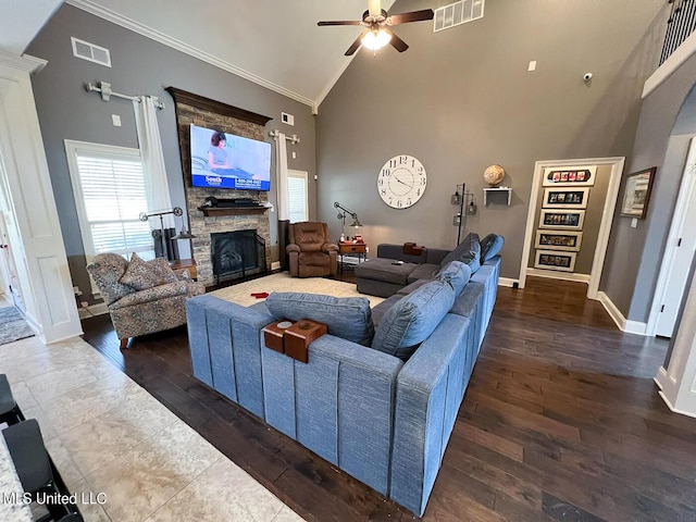 living room with high vaulted ceiling, a fireplace, ornamental molding, ceiling fan, and dark wood-type flooring