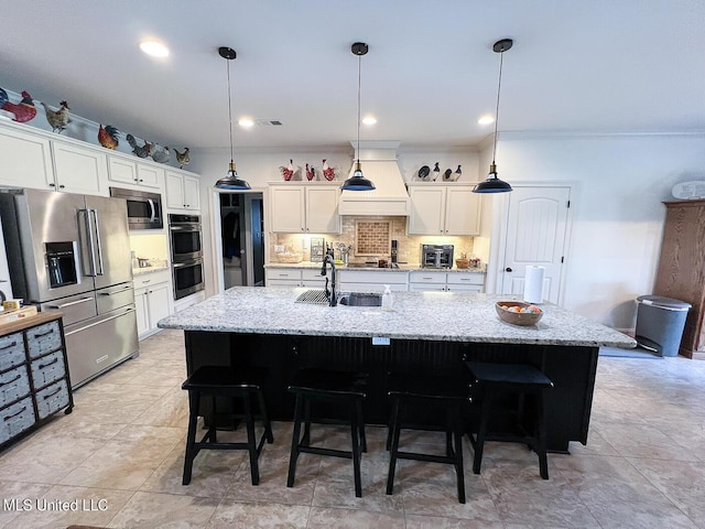 kitchen with stainless steel appliances, white cabinetry, hanging light fixtures, and a kitchen island with sink