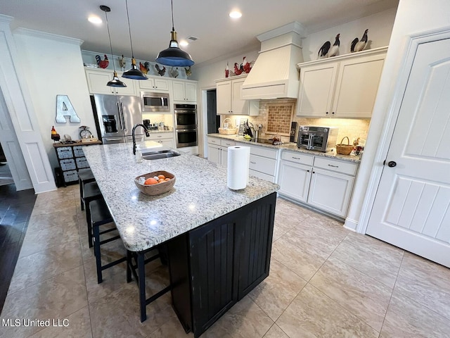 kitchen featuring sink, stainless steel appliances, a center island with sink, decorative light fixtures, and custom exhaust hood