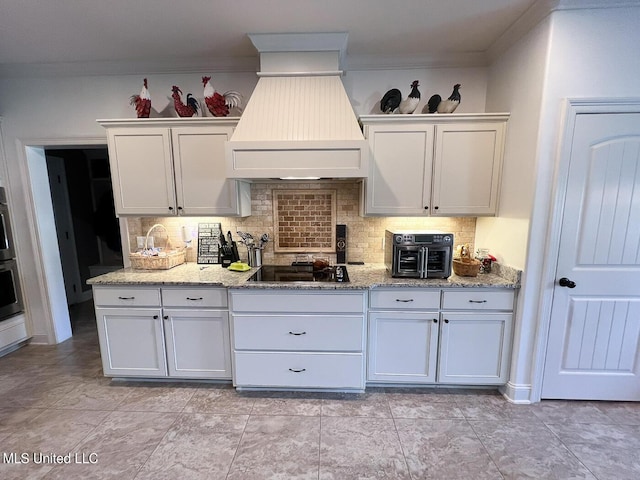 kitchen with white cabinetry, tasteful backsplash, ornamental molding, custom range hood, and black electric cooktop