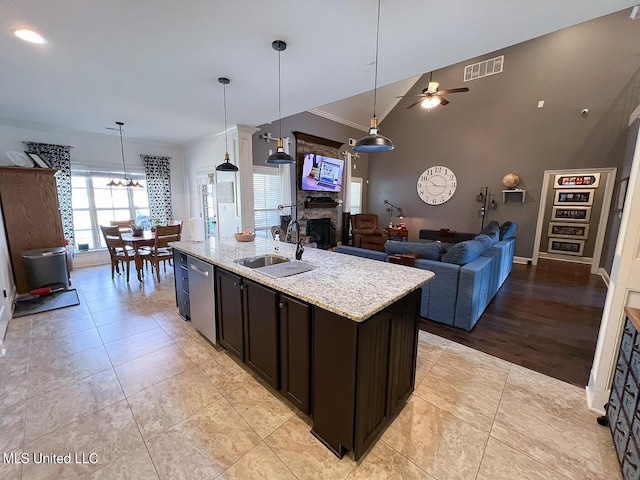 kitchen with sink, dishwasher, a kitchen island with sink, hanging light fixtures, and light stone counters