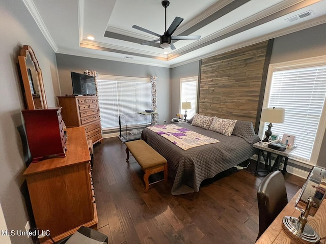 bedroom featuring crown molding, dark wood-type flooring, ceiling fan, wooden walls, and a raised ceiling