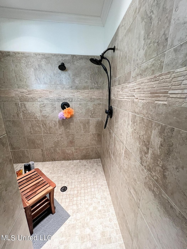 bathroom with crown molding and a tile shower