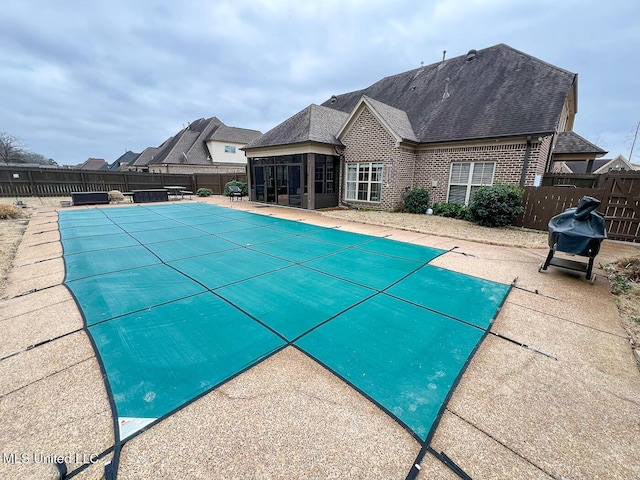 view of swimming pool featuring a grill, a patio, and a sunroom