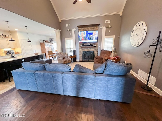 living room featuring a fireplace, decorative columns, sink, dark hardwood / wood-style flooring, and crown molding