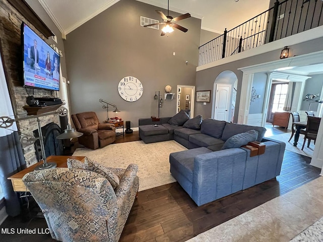 living room with ceiling fan, high vaulted ceiling, dark hardwood / wood-style floors, a fireplace, and ornamental molding