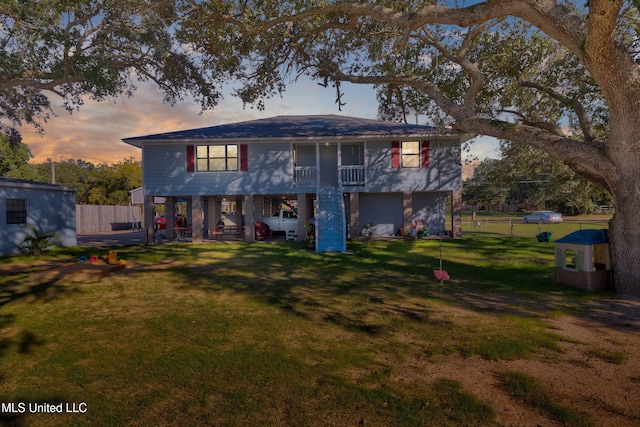 back house at dusk featuring a lawn and a carport