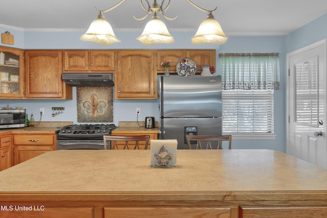 kitchen with a center island, an inviting chandelier, ornamental molding, appliances with stainless steel finishes, and decorative light fixtures