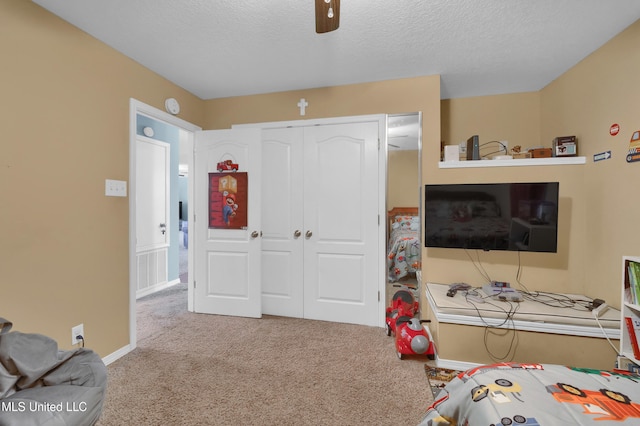 carpeted bedroom featuring ceiling fan, a closet, and a textured ceiling