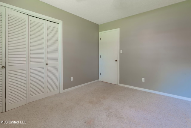 unfurnished bedroom featuring light carpet and a closet