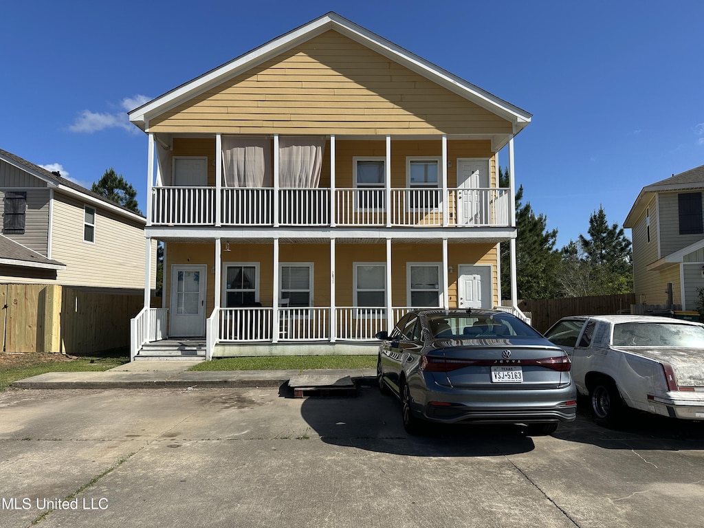 view of front of house with fence, covered porch, and a balcony