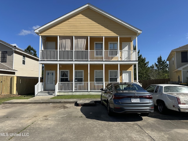 view of front of house with fence, covered porch, and a balcony