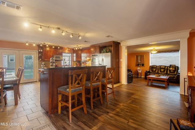 kitchen featuring french doors, kitchen peninsula, stainless steel appliances, dark wood-type flooring, and a breakfast bar area