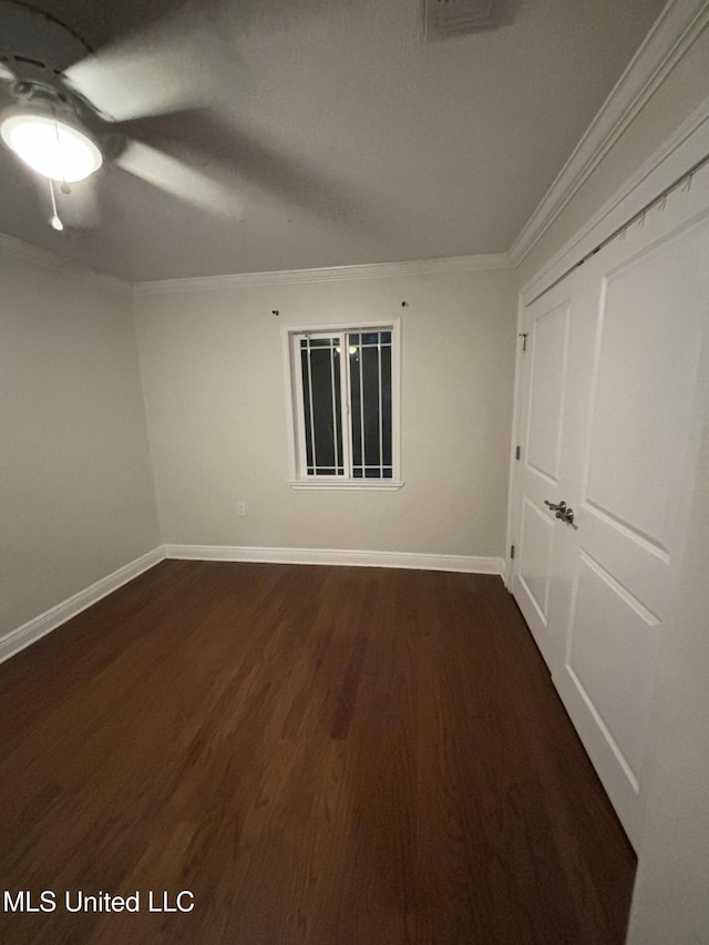 empty room featuring crown molding and dark wood-type flooring