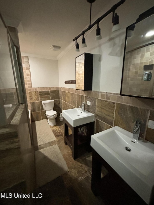 bathroom with vanity, toilet, crown molding, and tile walls