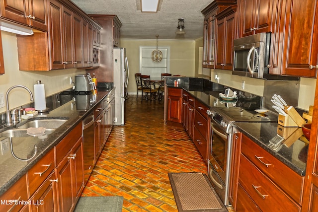 kitchen featuring sink, dark stone countertops, pendant lighting, a textured ceiling, and appliances with stainless steel finishes