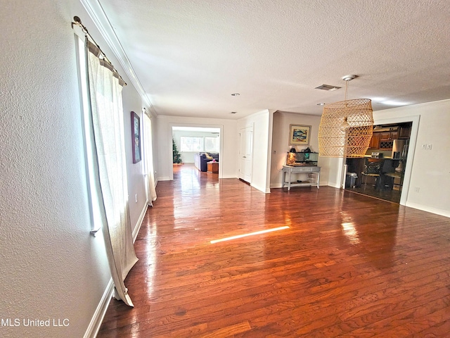 unfurnished living room with a textured ceiling, crown molding, and dark wood-type flooring