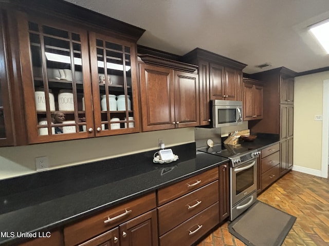 kitchen with dark brown cabinets, dark stone countertops, and stainless steel appliances