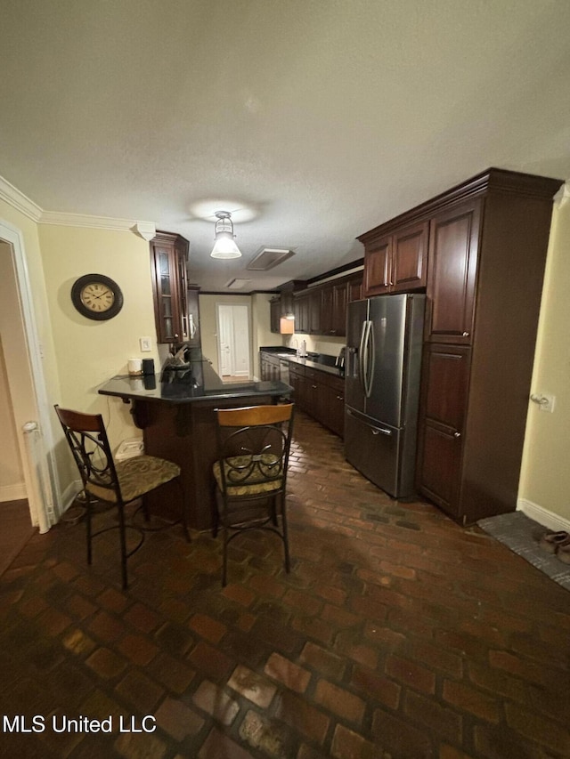 kitchen featuring a kitchen breakfast bar, crown molding, kitchen peninsula, dark brown cabinets, and stainless steel fridge with ice dispenser