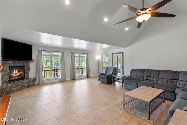 tiled living room featuring ceiling fan, a stone fireplace, and high vaulted ceiling