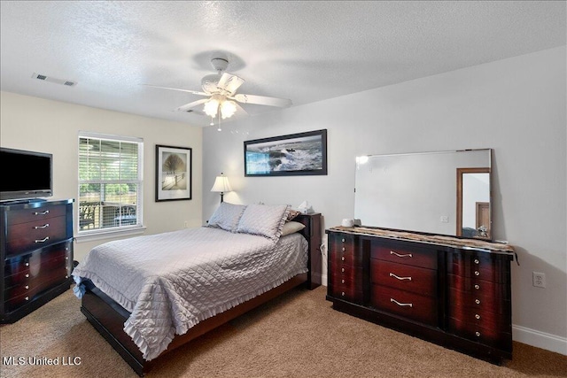 bedroom with a textured ceiling, light colored carpet, and ceiling fan