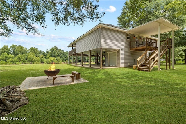 rear view of house featuring a patio, a deck, a yard, and a fire pit