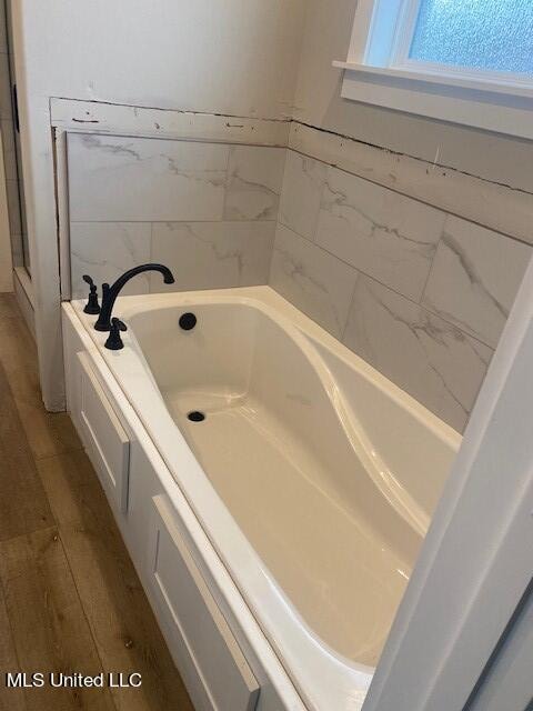 bathroom featuring wood-type flooring and a tub