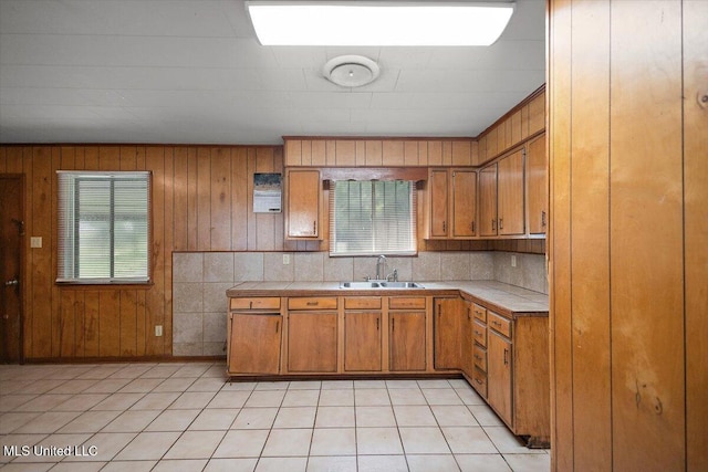 308 Asbury Dr, Hazlehurst, MS 39083 - kitchen with tile counters, brown cabinets, healthy amount of natural light, wood walls, and light tile patterned floors