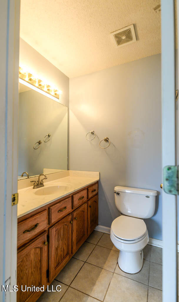 796 Steward Ln, Southaven, MS 38671 - bathroom featuring toilet, vanity, tile patterned flooring, baseboards, and a textured ceiling