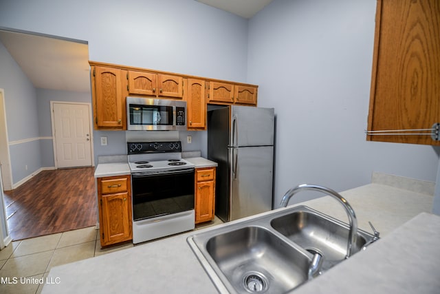 796 Steward Ln, Southaven, MS 38671 - kitchen with stainless steel appliances, a sink, light countertops, brown cabinets, and light tile patterned flooring
