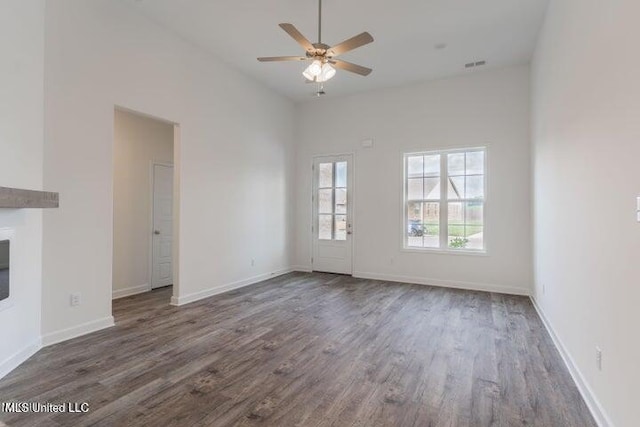 unfurnished living room featuring a high ceiling, dark hardwood / wood-style floors, and ceiling fan