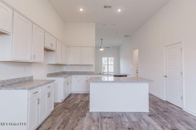 kitchen featuring white cabinets, a center island, ceiling fan, and sink