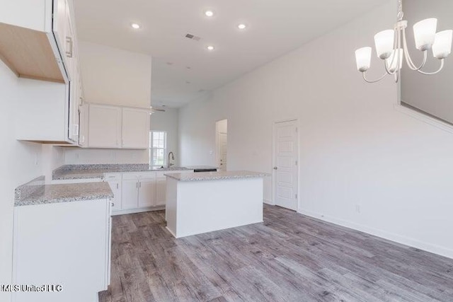 kitchen with sink, a center island, hanging light fixtures, light hardwood / wood-style floors, and white cabinets