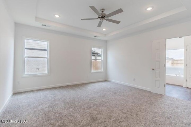 carpeted empty room featuring ceiling fan and a tray ceiling