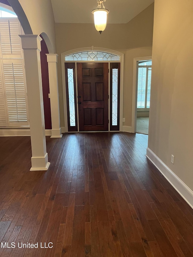 entrance foyer with ornate columns and dark wood-type flooring