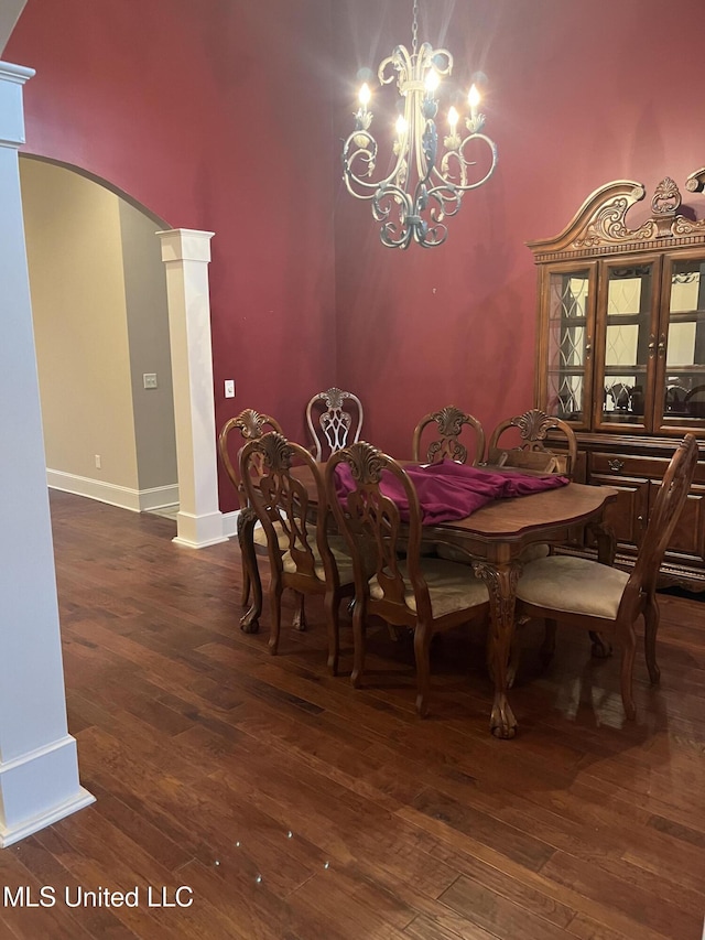 dining area with a high ceiling, ornate columns, dark wood-type flooring, and a notable chandelier