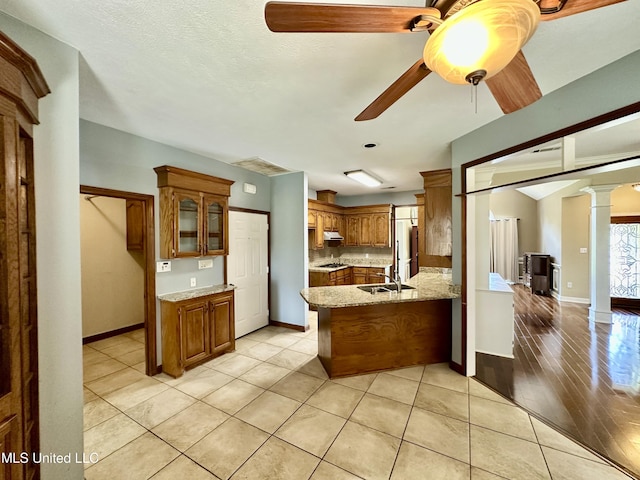 kitchen featuring a peninsula, brown cabinetry, baseboards, and a ceiling fan