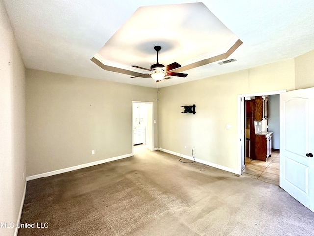 unfurnished room with a ceiling fan, a tray ceiling, visible vents, and light colored carpet