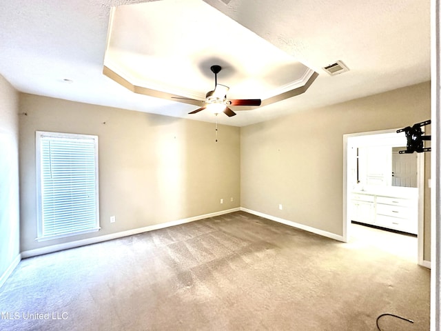 empty room with baseboards, a raised ceiling, and carpet floors