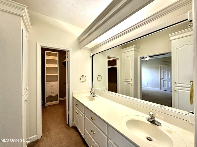 bathroom featuring a ceiling fan, a textured ceiling, double vanity, and a sink