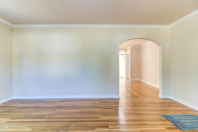 spare room featuring light hardwood / wood-style flooring, ornamental molding, and a chandelier