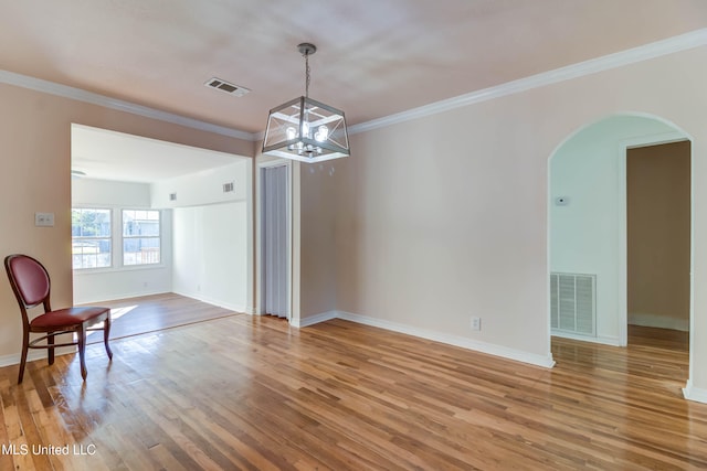 spare room with ornamental molding, a chandelier, and hardwood / wood-style floors