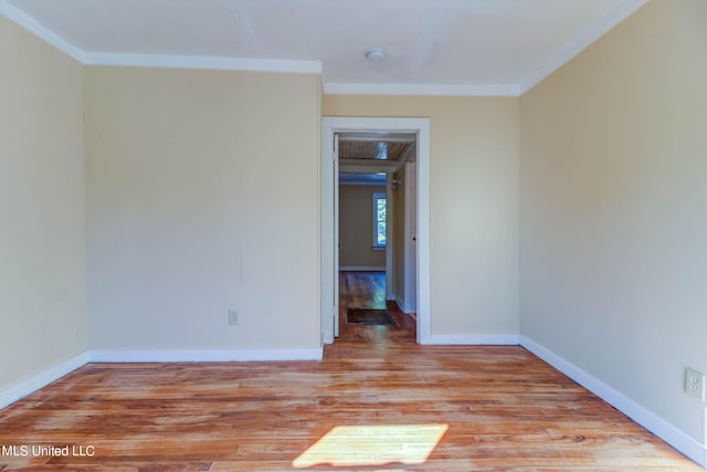 spare room featuring crown molding and light hardwood / wood-style floors