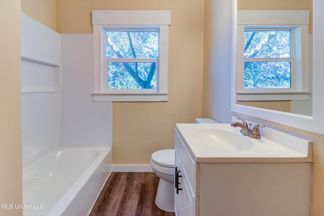 full bathroom featuring a healthy amount of sunlight, vanity, hardwood / wood-style flooring, and toilet